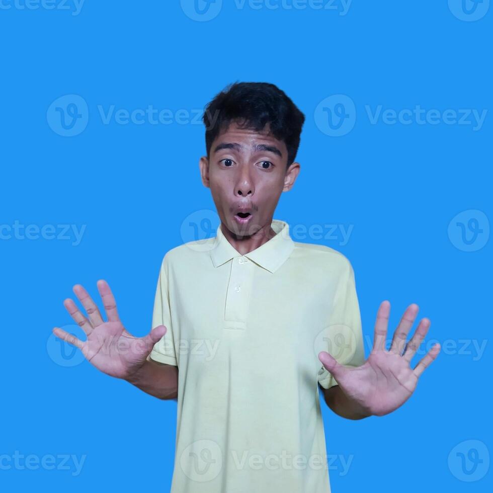 young asian man hands stop. with a serious face wearing a yellow t-shirt, isolated on a blue background photo
