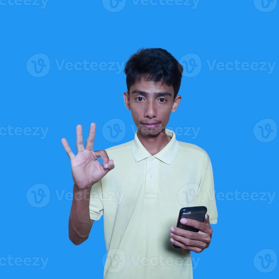 Asian man smiling face with okay gesture, isolated on blue background photo