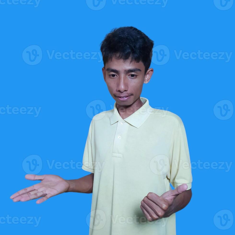 young asian man with a surprised face facing the camera, with both hands to the side, wearing a yellow blue t-shirt, isolated on a purple background. photo