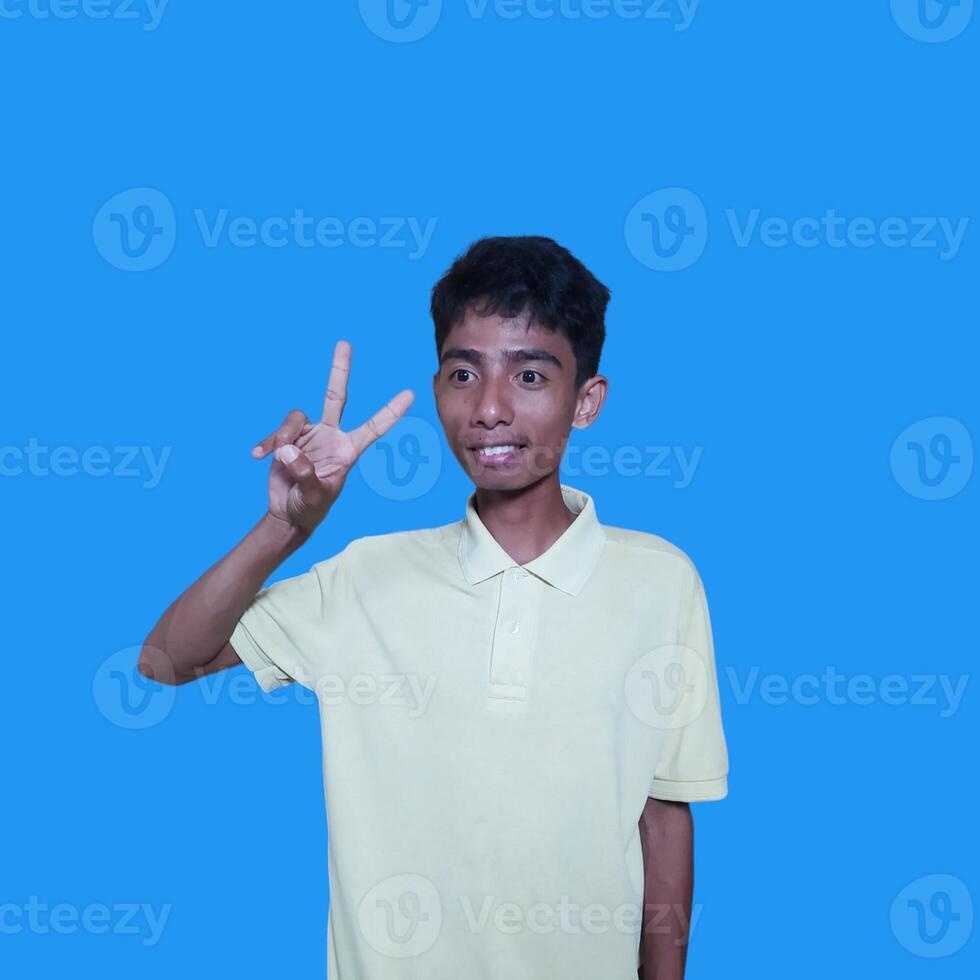 Excited Asian man wearing yellow t-shirt giving number 12345 hand gesture. blue background photo