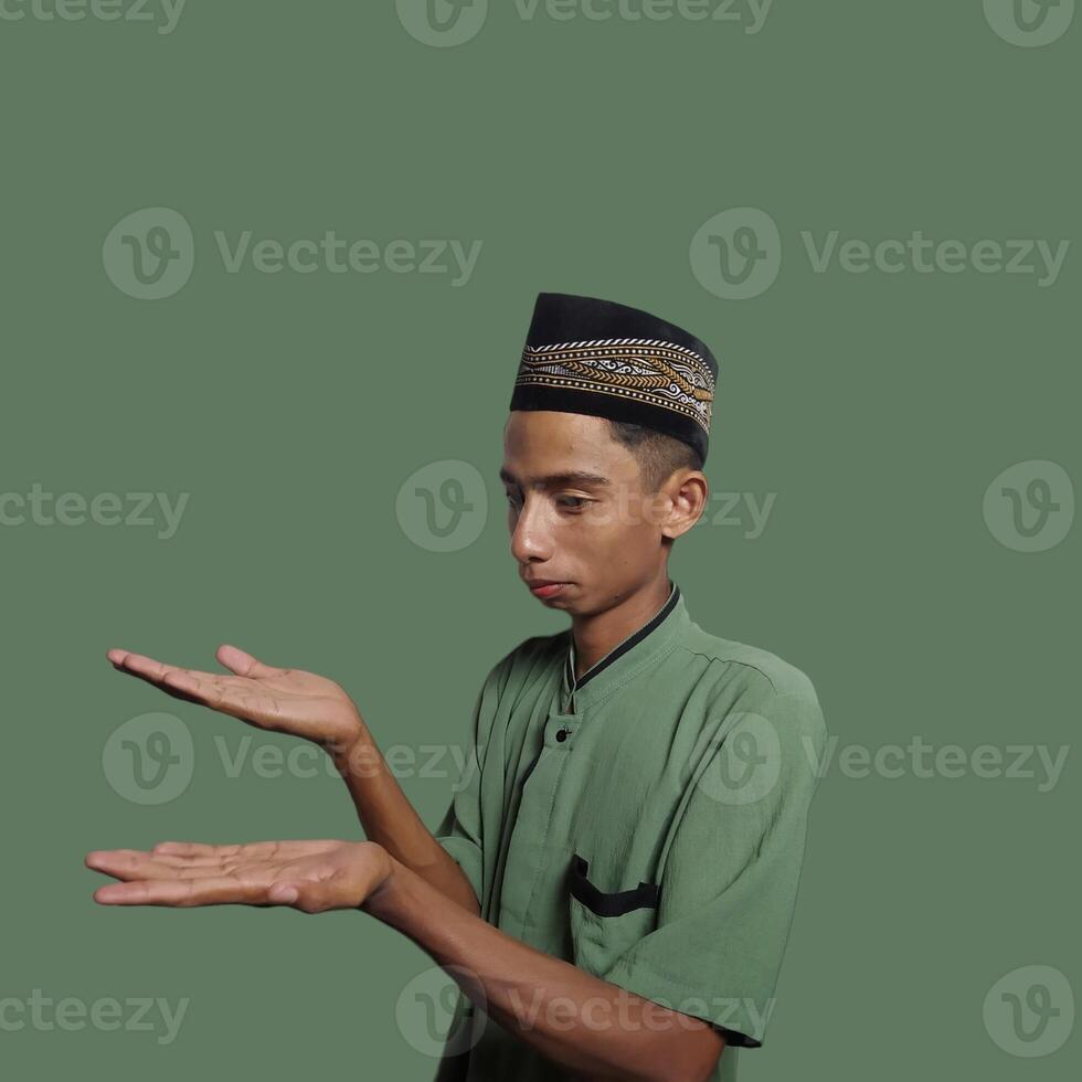 Excited Asian man wearing green t-shirt pointing at copy space on the side, isolated on purple background. photo
