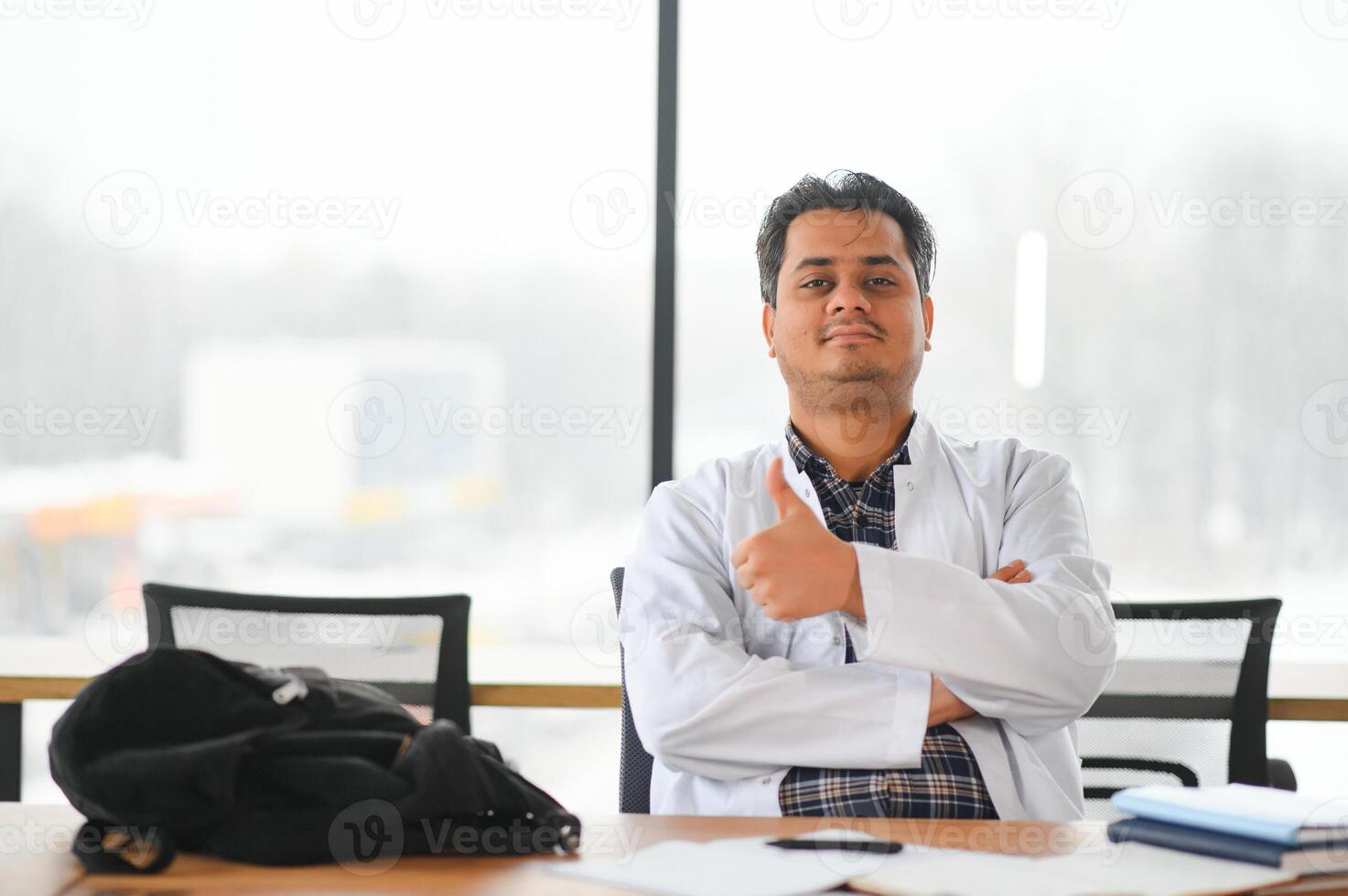 retrato de un joven indio masculino médico estudiante en un blanco Saco ondulación foto