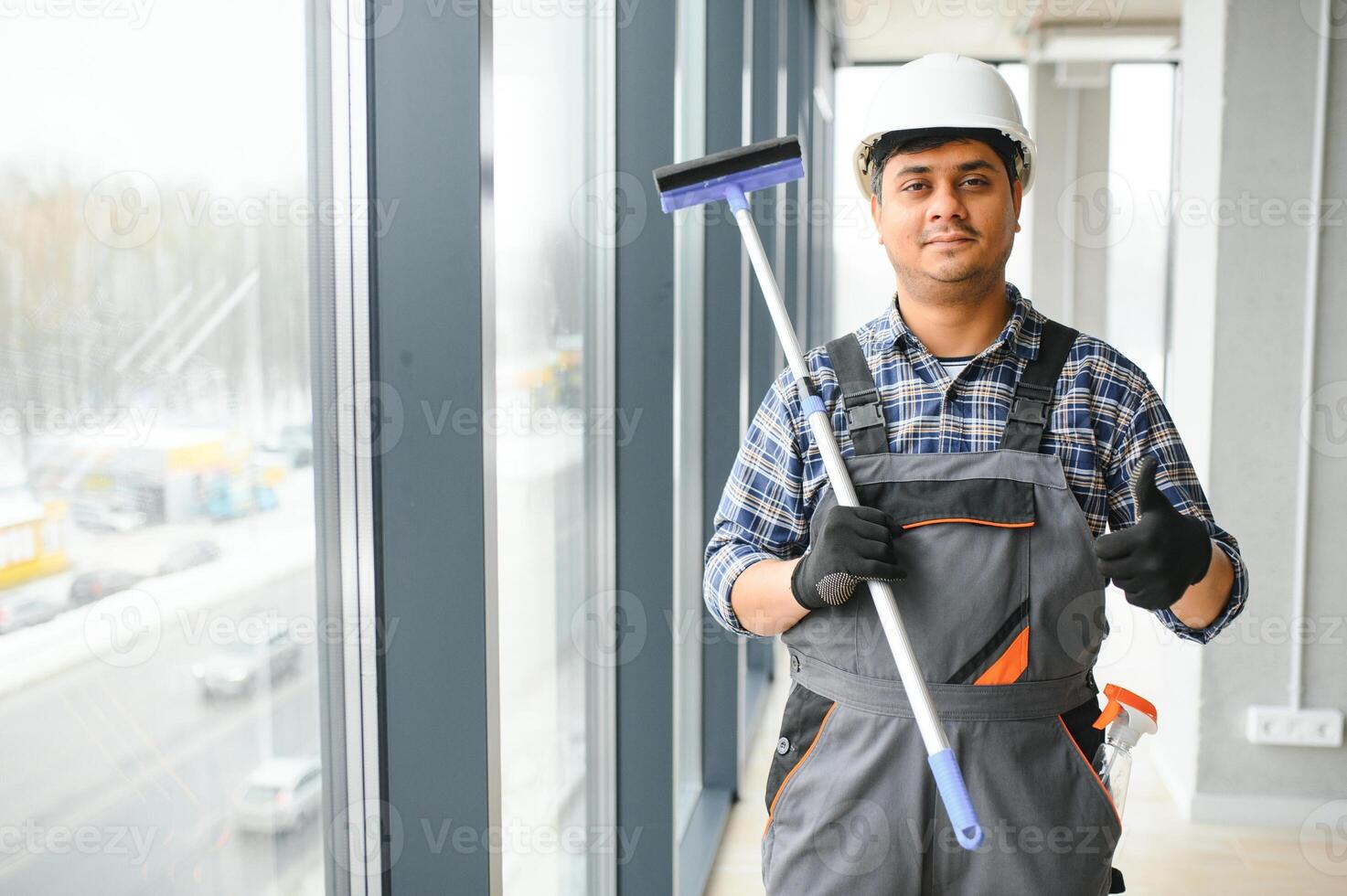 Male professional cleaning service worker cleans the windows and shop windows of a store with special equipment photo