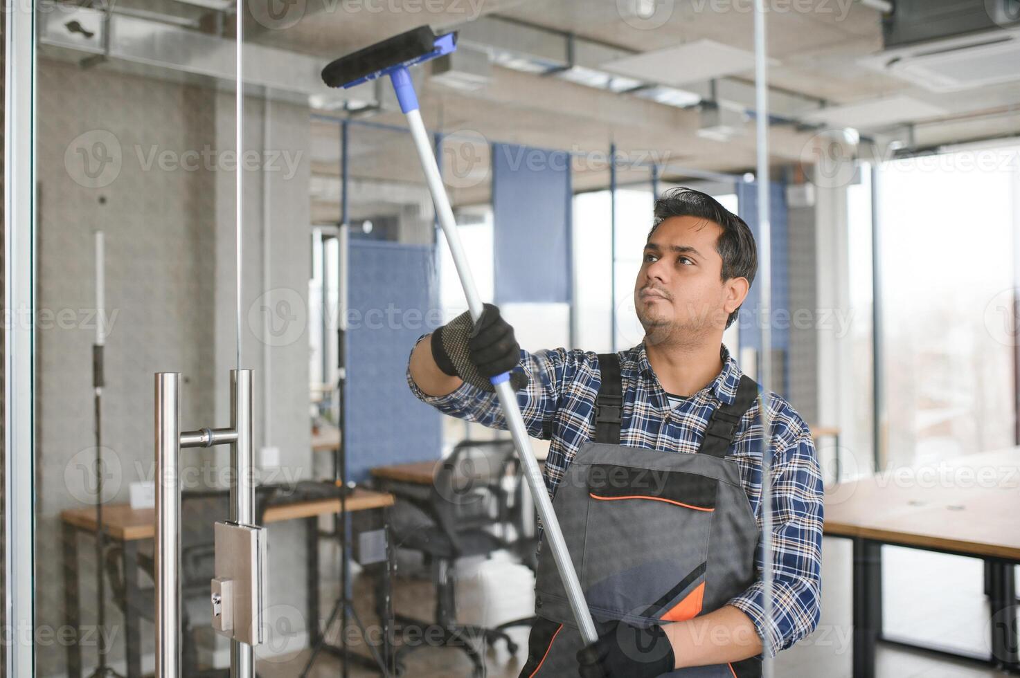 masculino profesional limpieza Servicio trabajador en mono limpia el ventanas y tienda ventanas foto