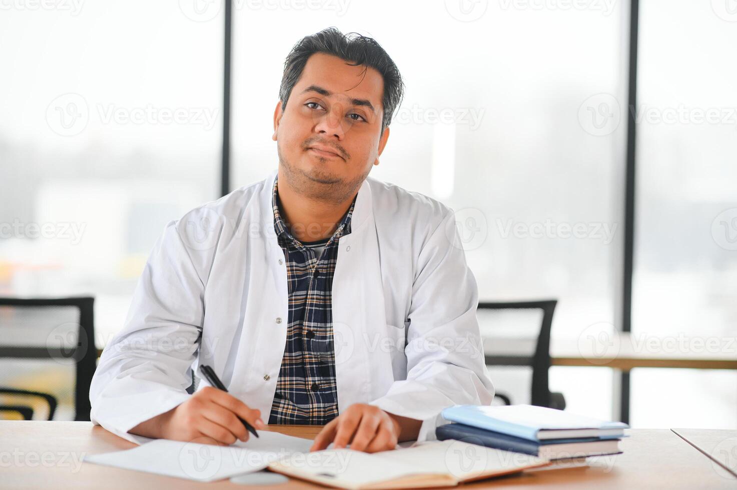 Portrait of a young Indian male medical student in a white coat waving photo