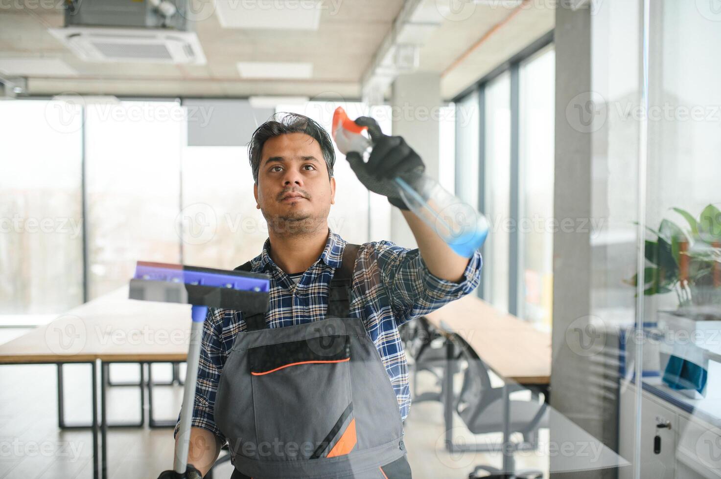 Male professional cleaning service worker cleans the windows and shop windows of a store with special equipment photo