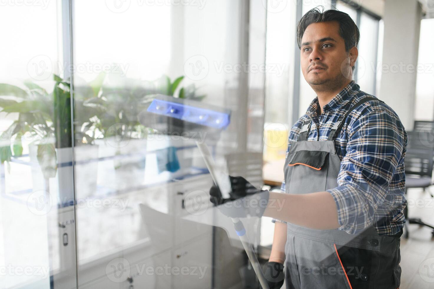 Male professional cleaning service worker cleans the windows and shop windows of a store with special equipment photo