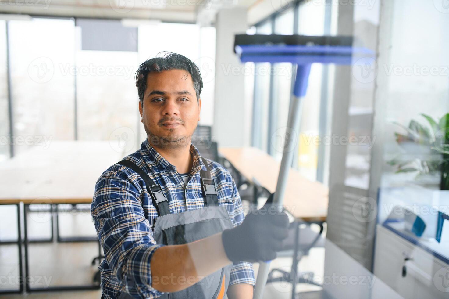 Male professional cleaning service worker cleans the windows and shop windows of a store with special equipment photo