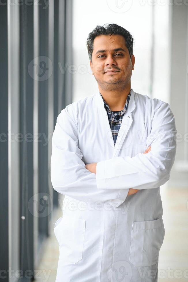 Portrait of male indian doctor on clinic corridor as background. photo
