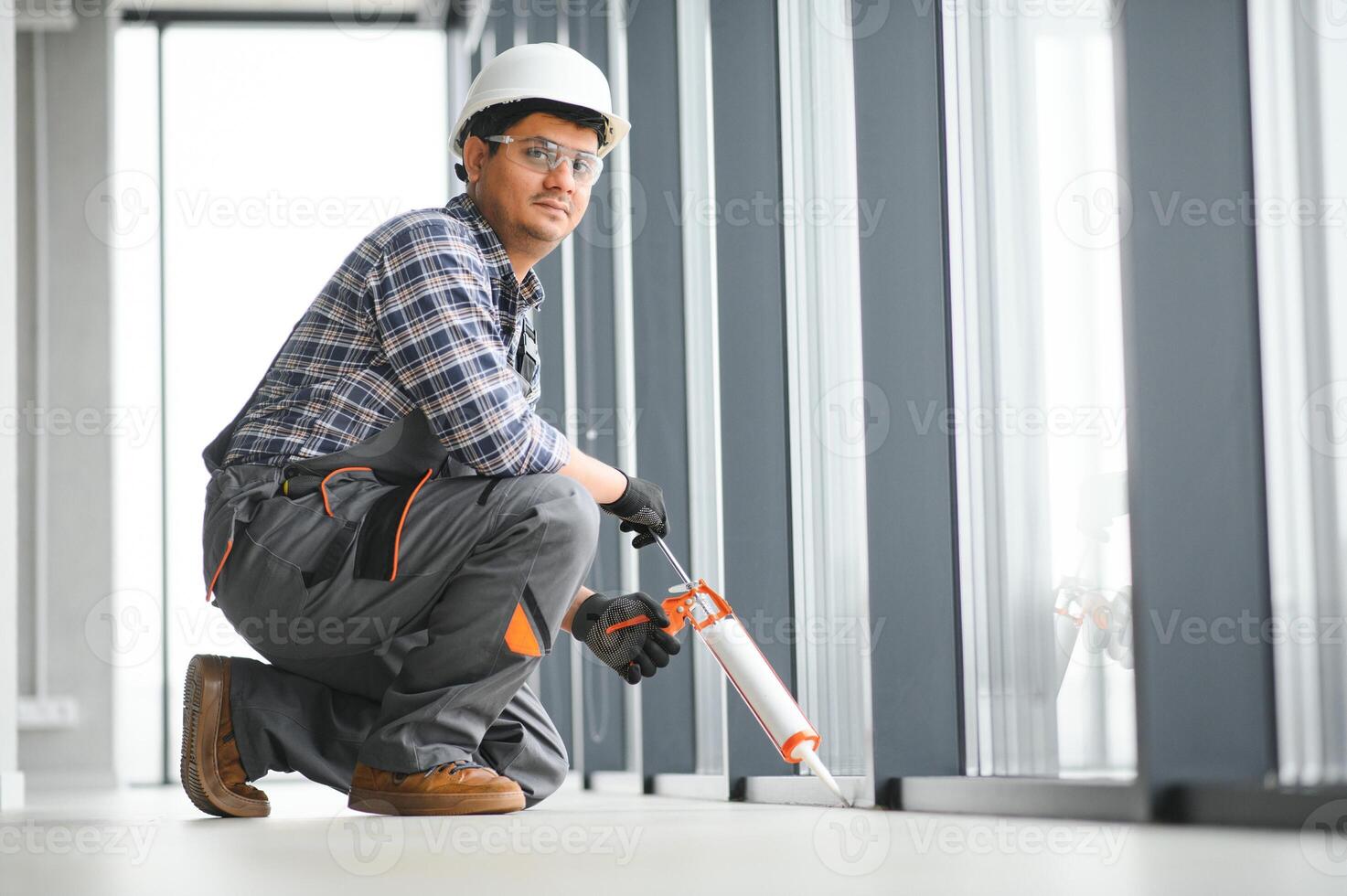 Workman in overalls installing or adjusting plastic windows photo