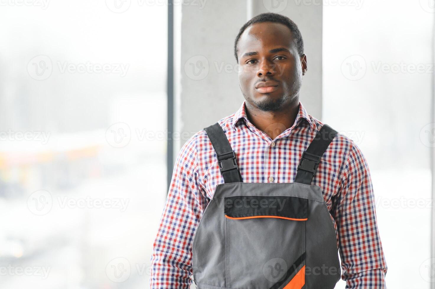 Portrait of handsome African worker or engineer in overalls and hard hat photo