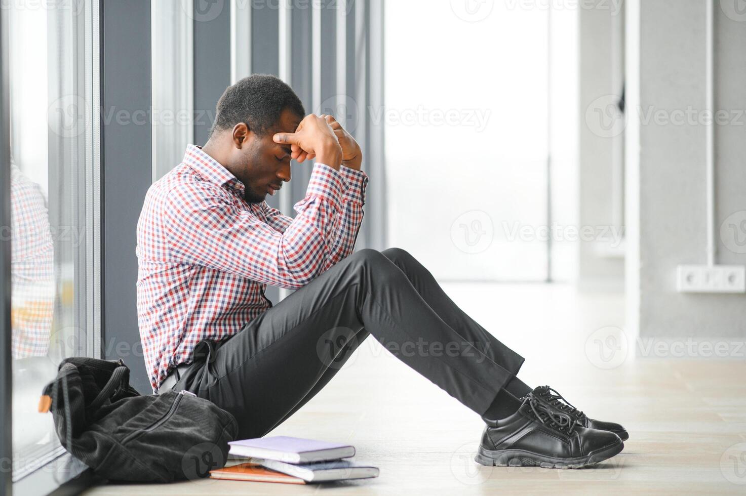 School bullying. Afro american male teenager desperate seated in school hallway photo