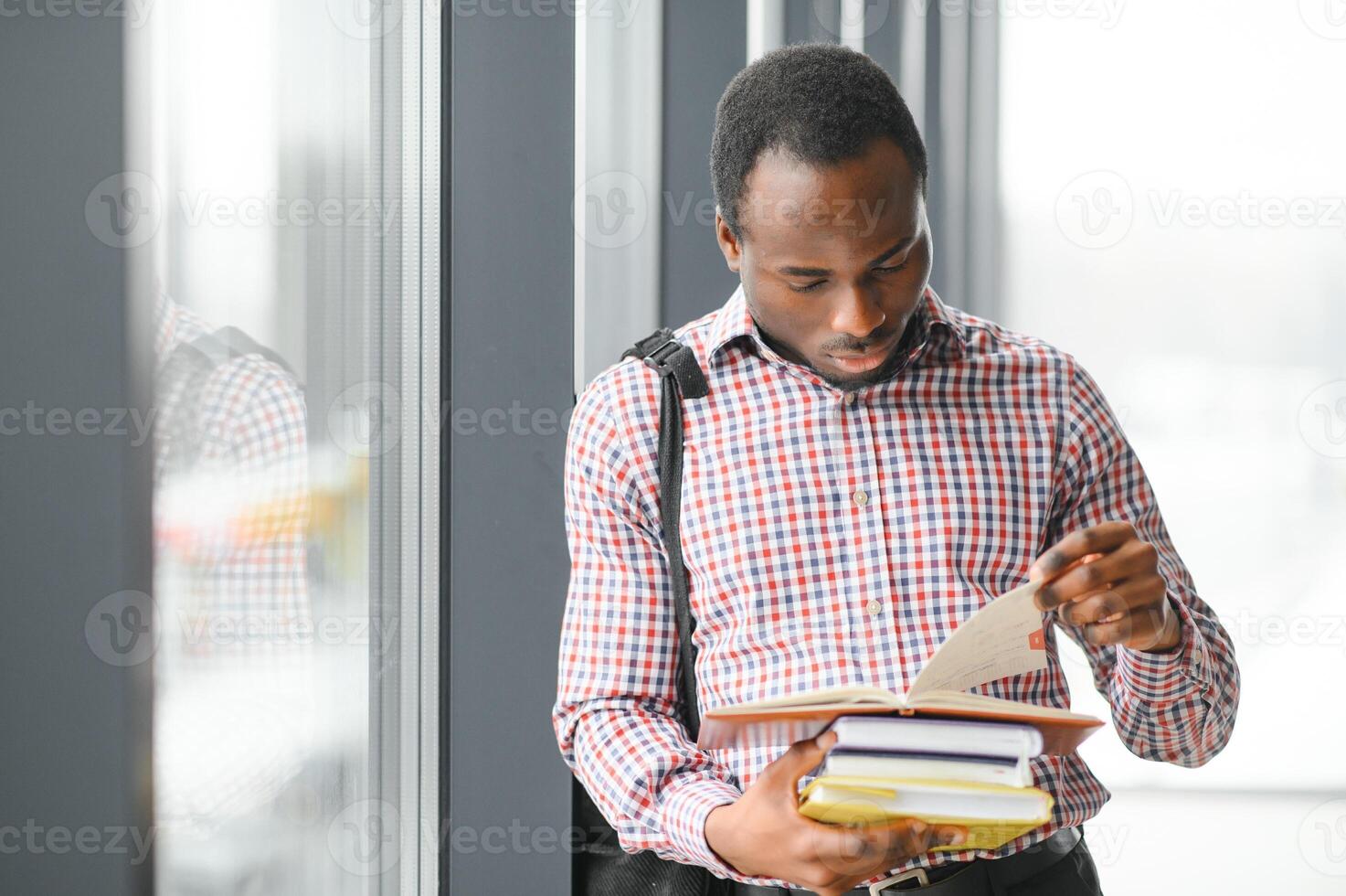 handsome college boy holding books on campus photo