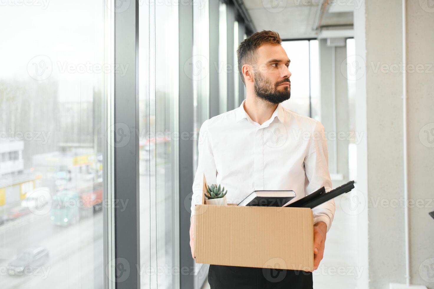 Sad Fired. Let Go Office Worker Packs His Belongings into Cardboard Box and Leaves Office. Workforce Reduction, Downsizing, Reorganization, Restructuring, Outsourcing. Mass Unemployment Market Crisis photo