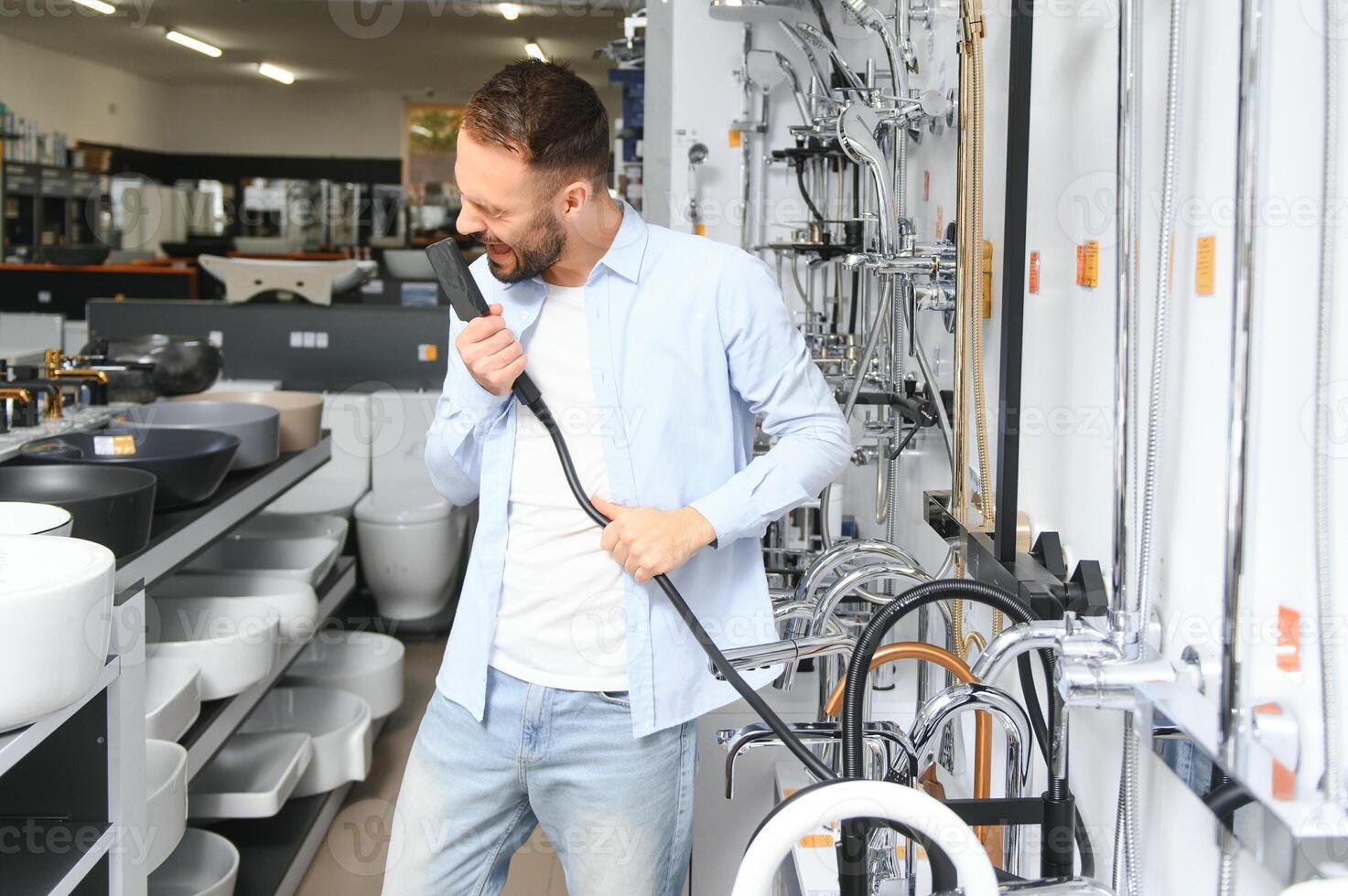 A large selection of water faucets. Man chooses a products in a sanitary ware store photo