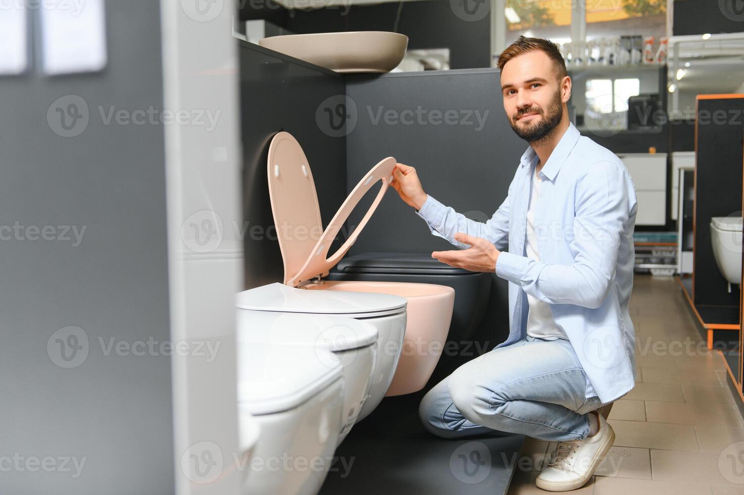 in a plumbing store, a man chooses a new toilet bowl photo