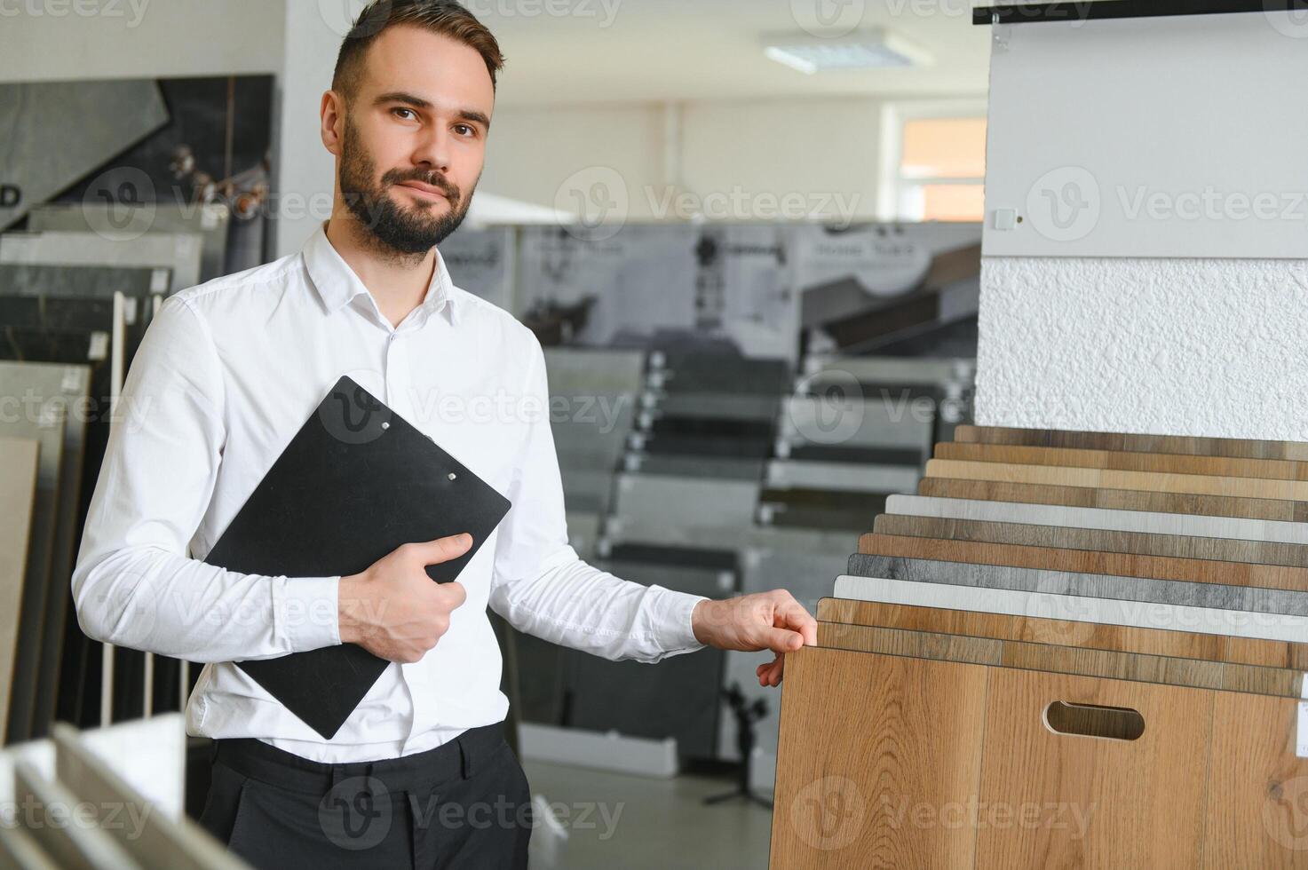 Portrait of a ceramic tile seller. The seller stands against the background of a large assortment of tiles photo