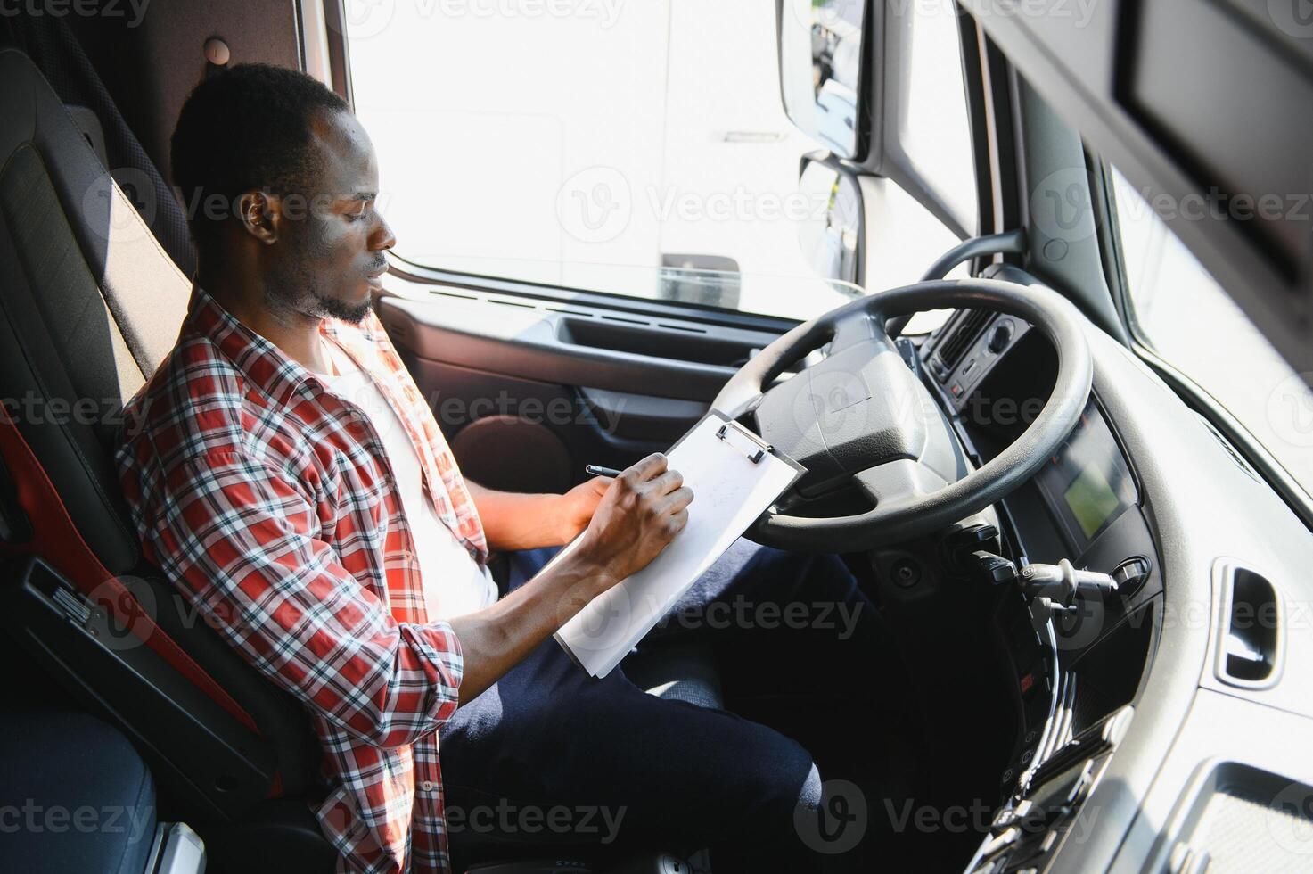 Professional african american truck driver in casual clothes driving truck vehicle going for a long transportation route. photo