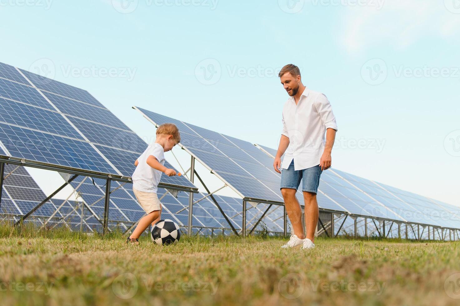 Father and son playing football in garden of solar paneled photo