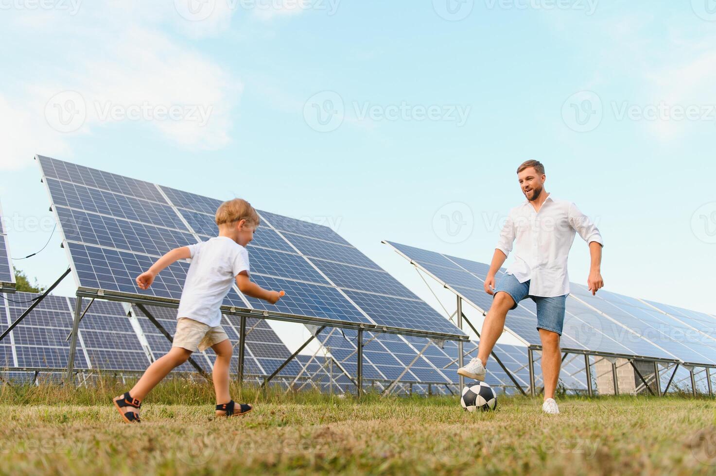 Father and son playing football in garden of solar paneled photo