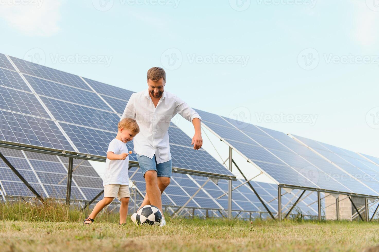 Father and son playing football in garden of solar paneled photo