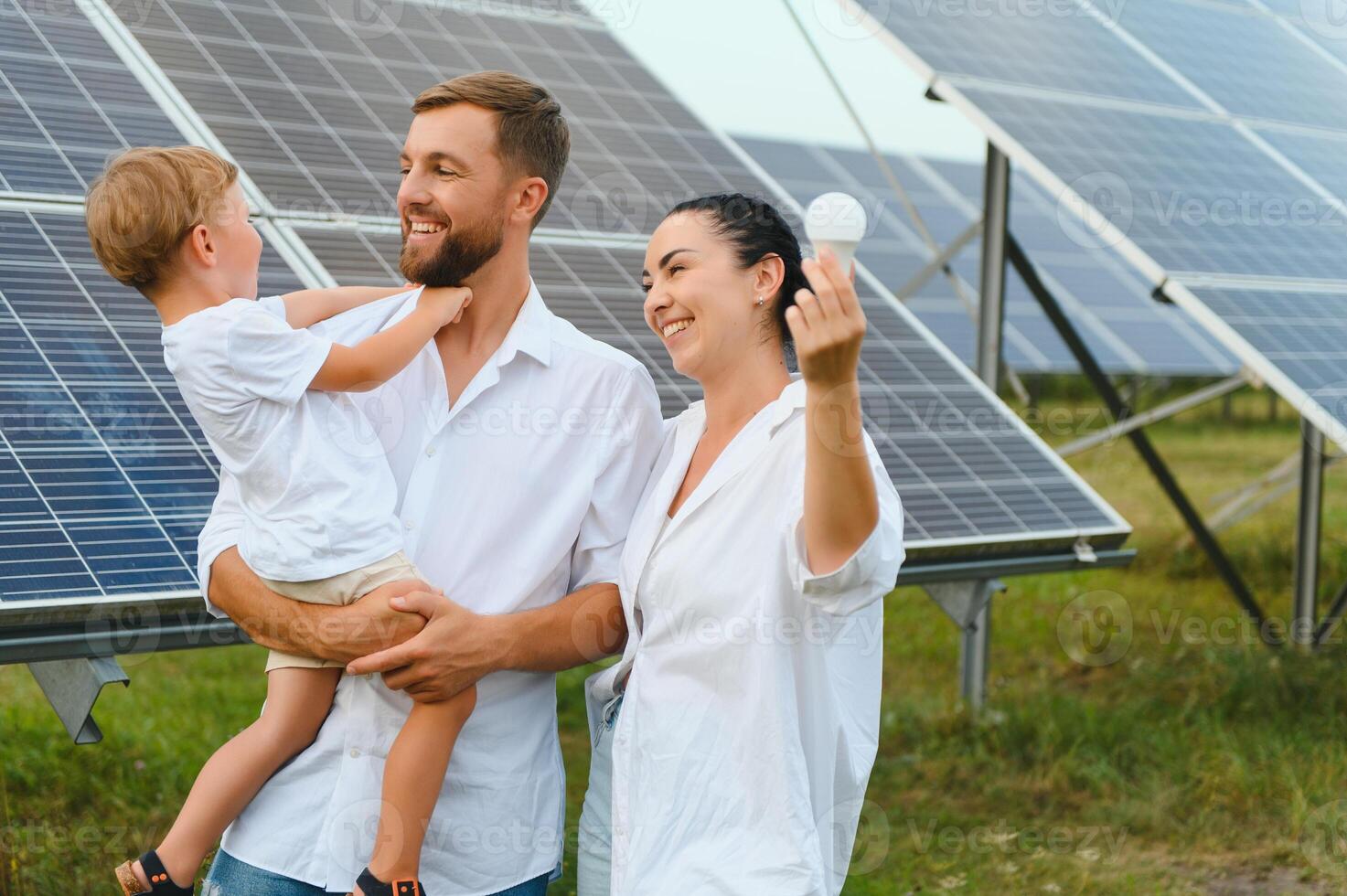 Young family of three is crouching near photovoltaic solar panel, little boy and parents. modern family concept. The concept of green energy photo