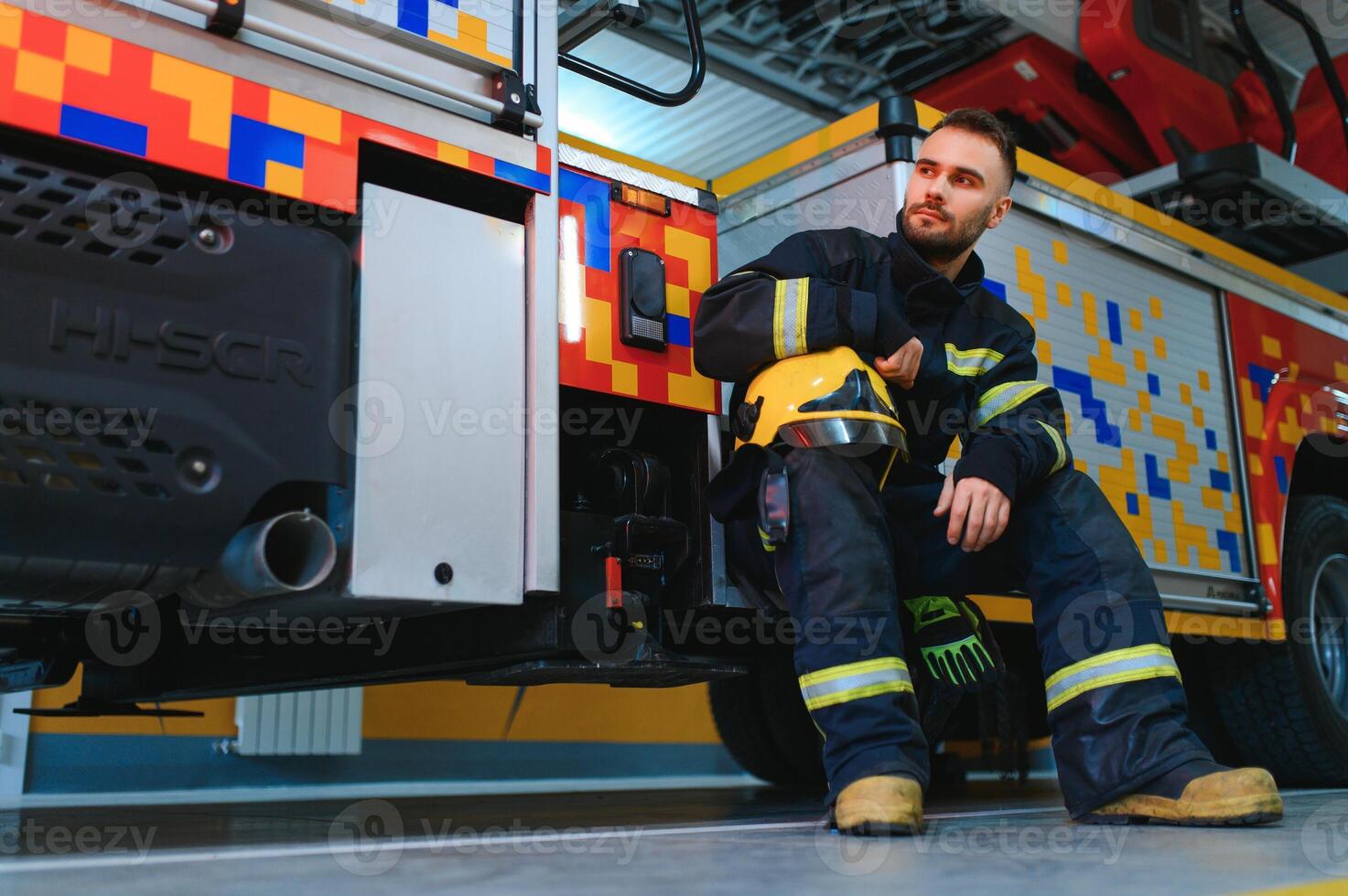 Photo of young fireman near fire engine