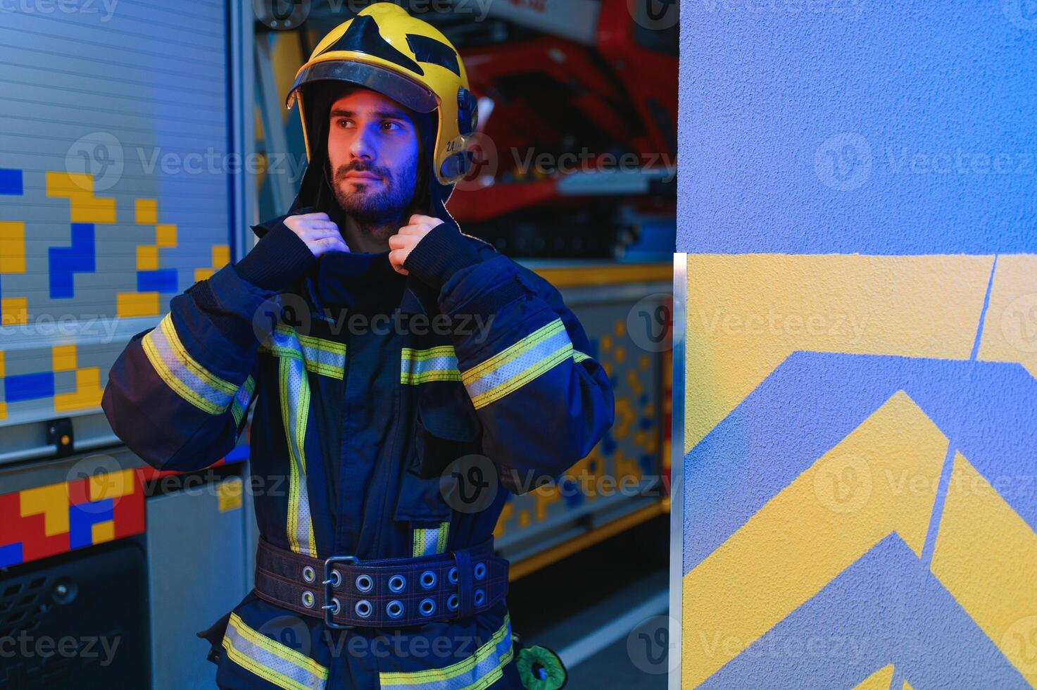 fireman in protective uniform standing near fire engine on station photo