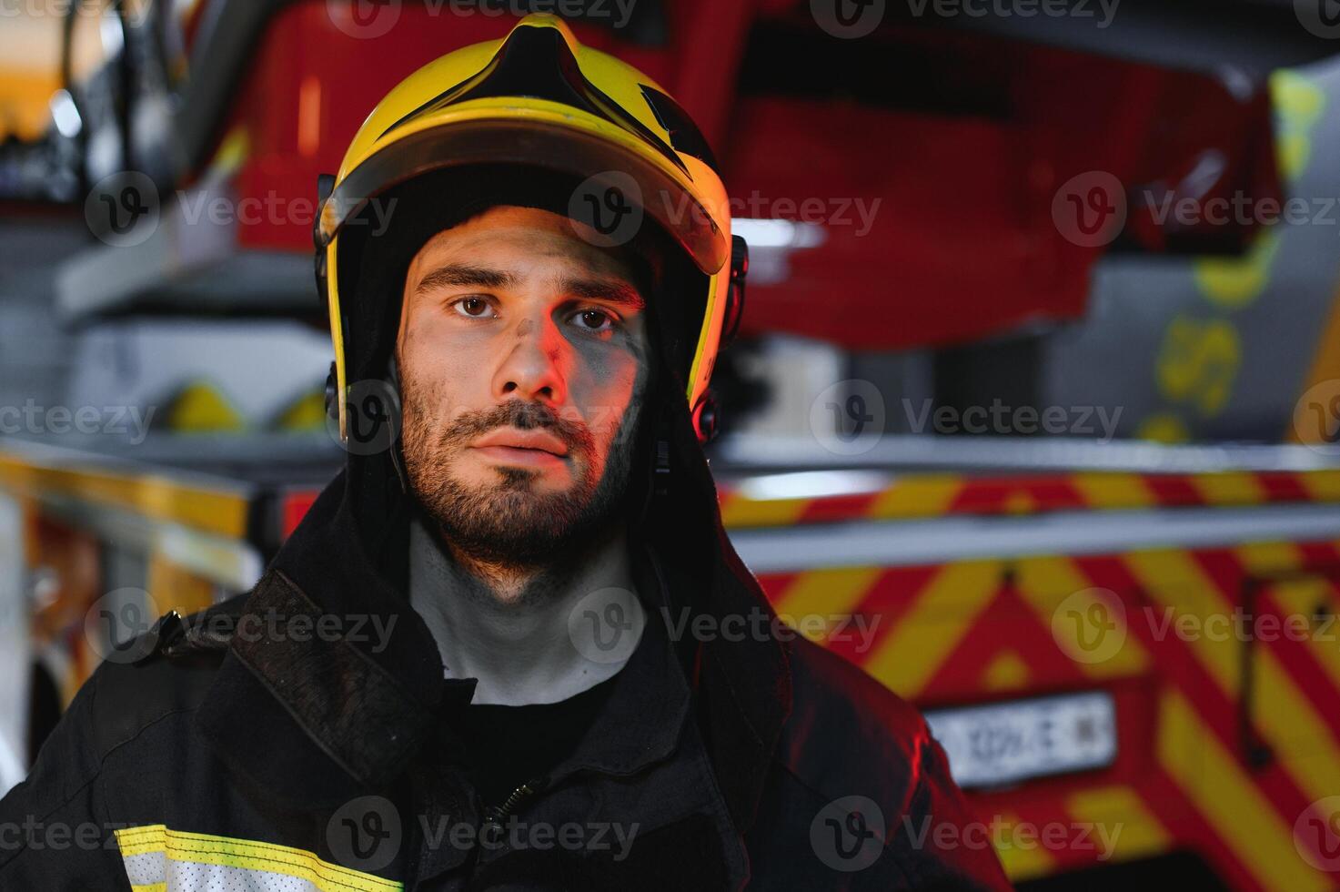 Portrait of a firefighter in a protective suit and a protective helmet standing by a fire engine after working on a fire. Close-up image photo