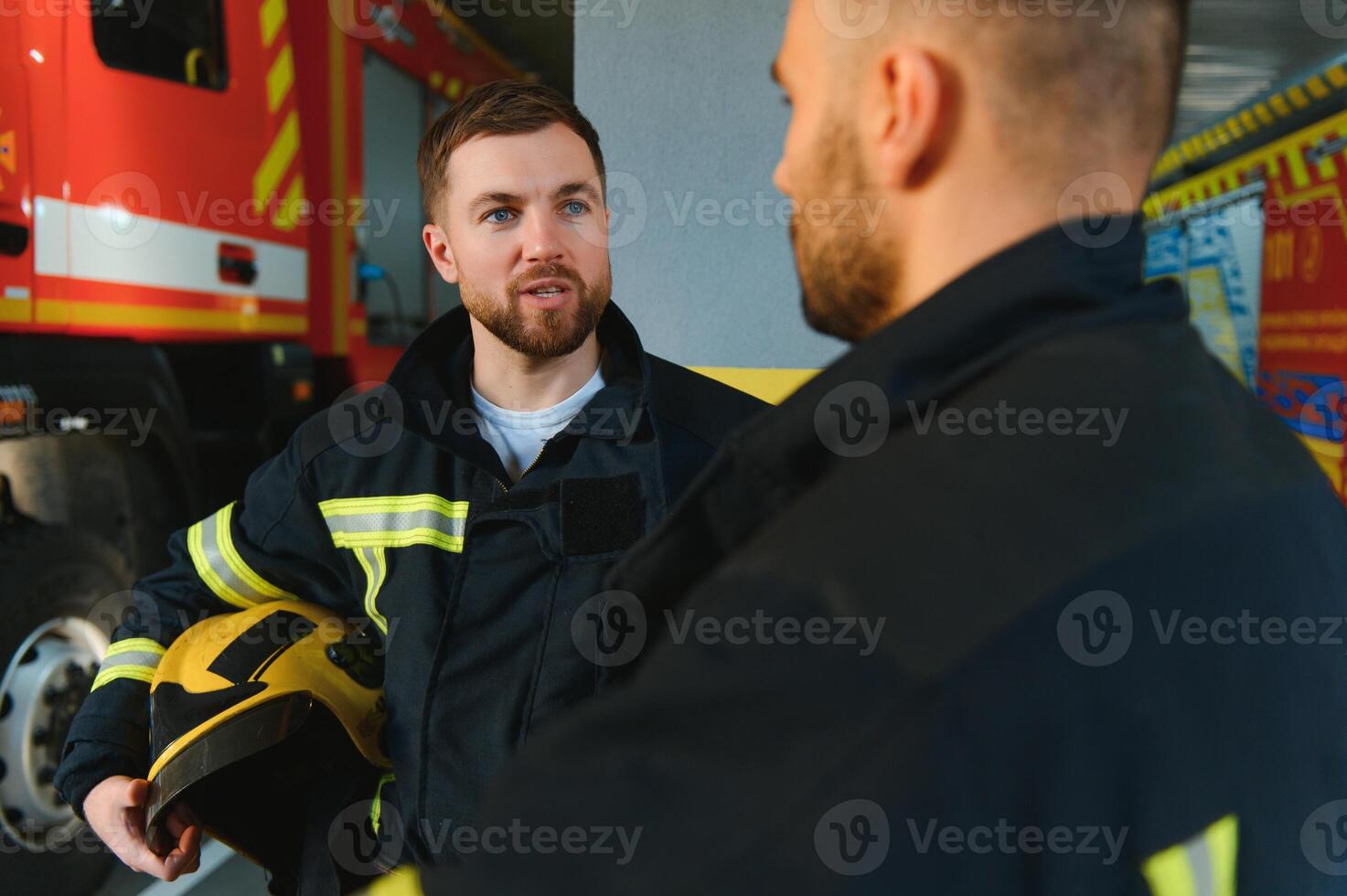 Group of firefighters at the emergency vehicle in the fire station photo