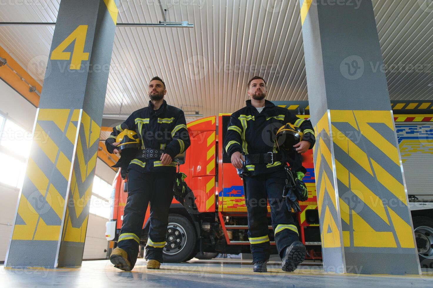 Group of firefighters at the emergency vehicle in the fire station photo