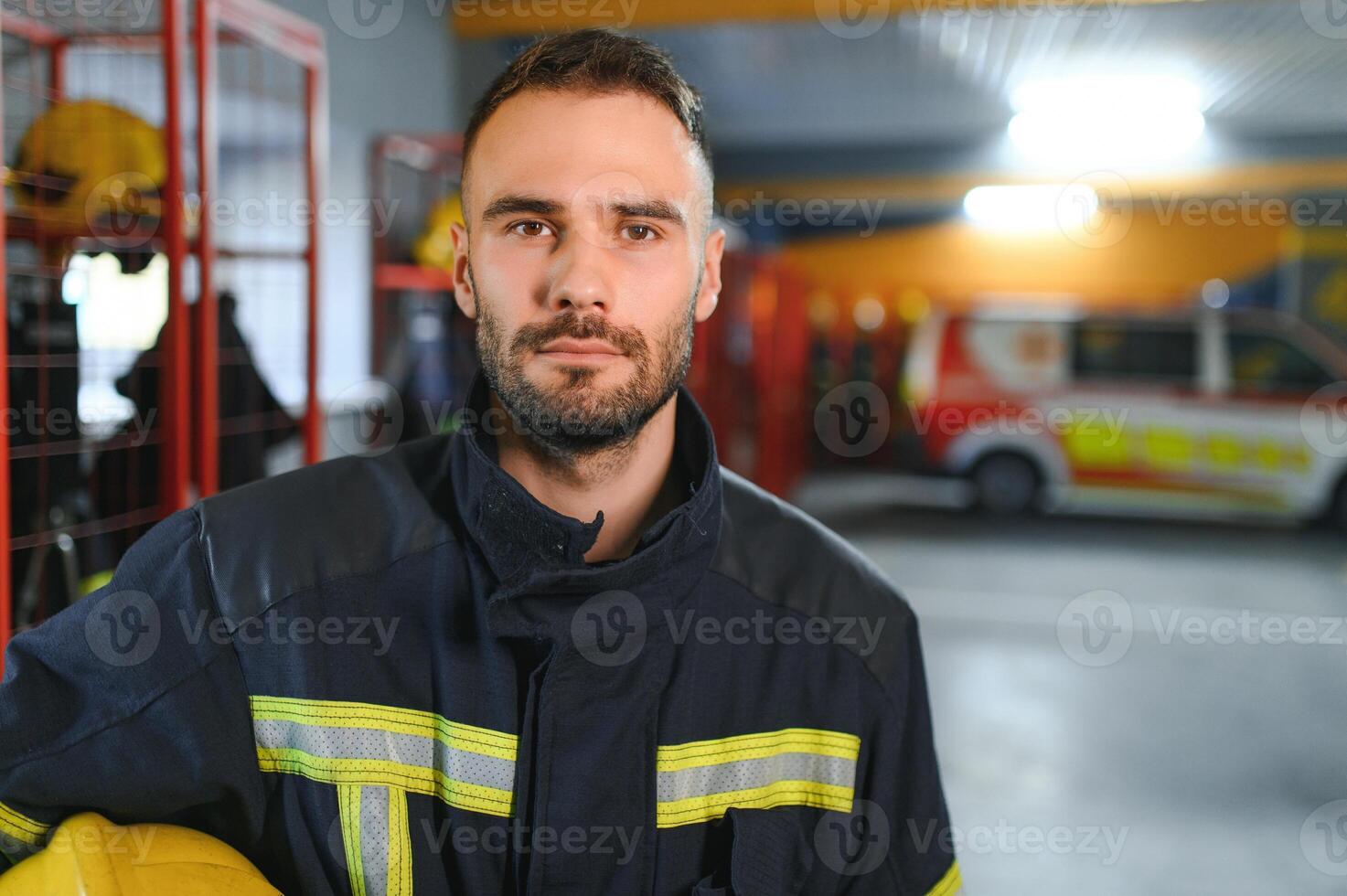 Fireman wearing protective uniform standing in fire department at fire station photo