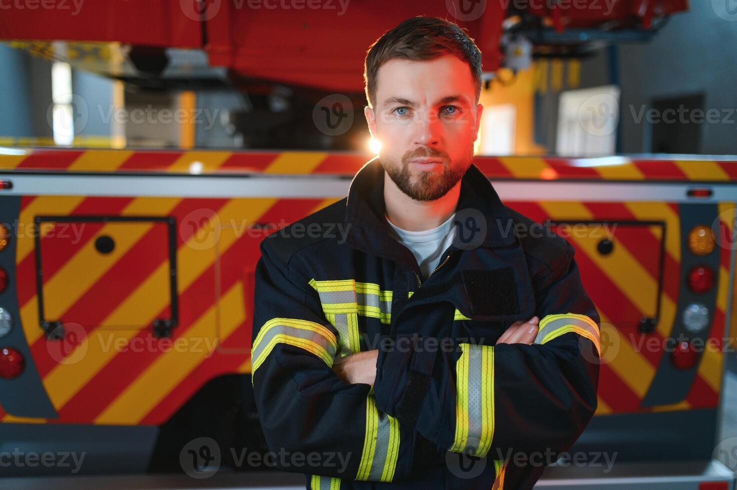 fireman in protective uniform standing near fire engine on station photo