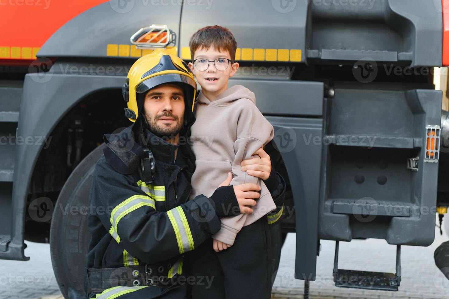 A firefighter take a little child boy to save him. Fire engine car on background photo