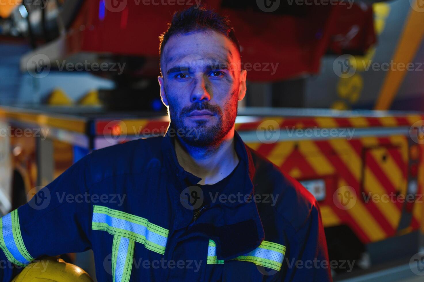 fireman in protective uniform standing near fire engine on station photo