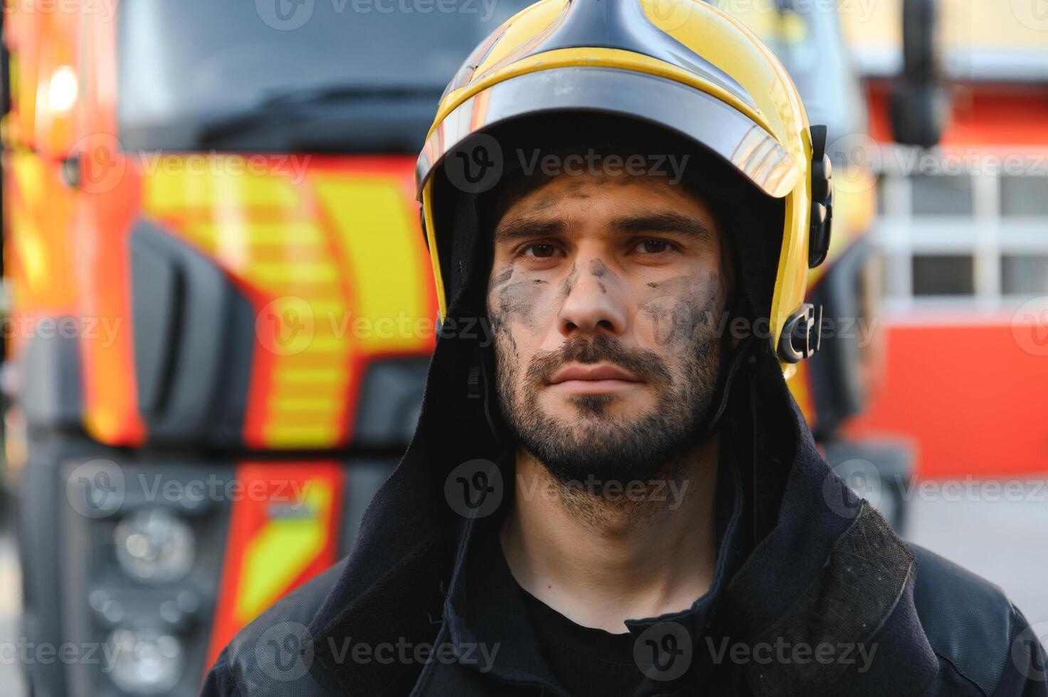 fireman in protective uniform standing near fire engine on station photo