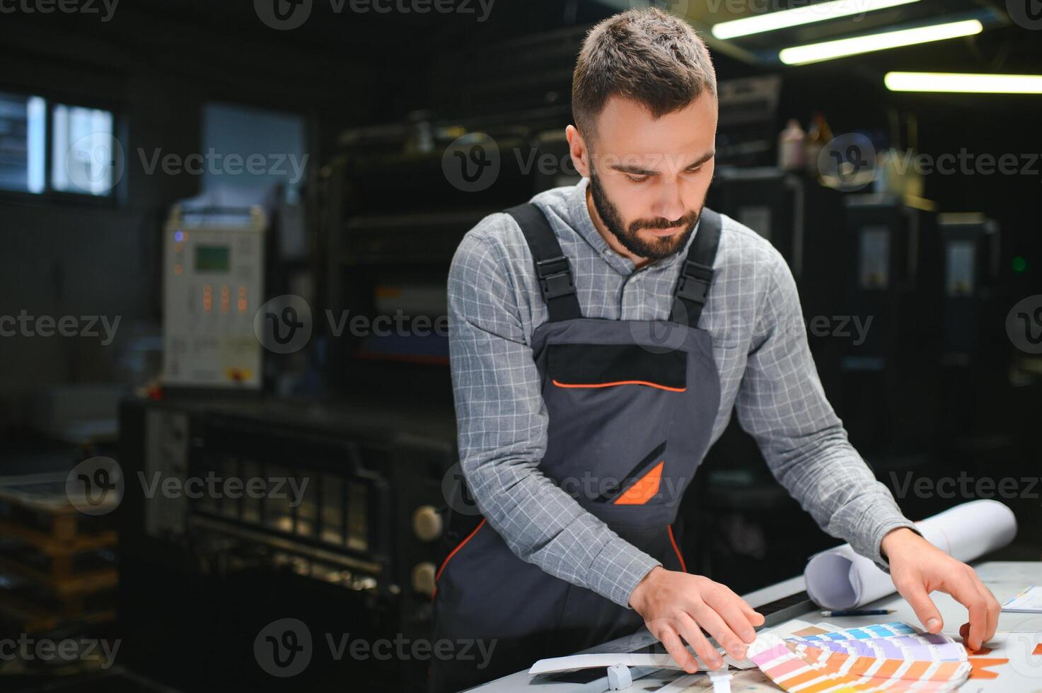 Man working in printing house with paper and paints photo