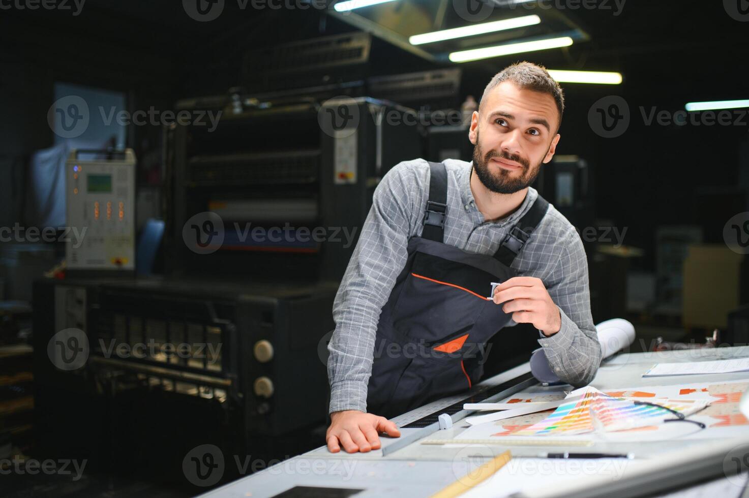 Print house worker controlling printing process quality and checking colors with magnifying glass photo