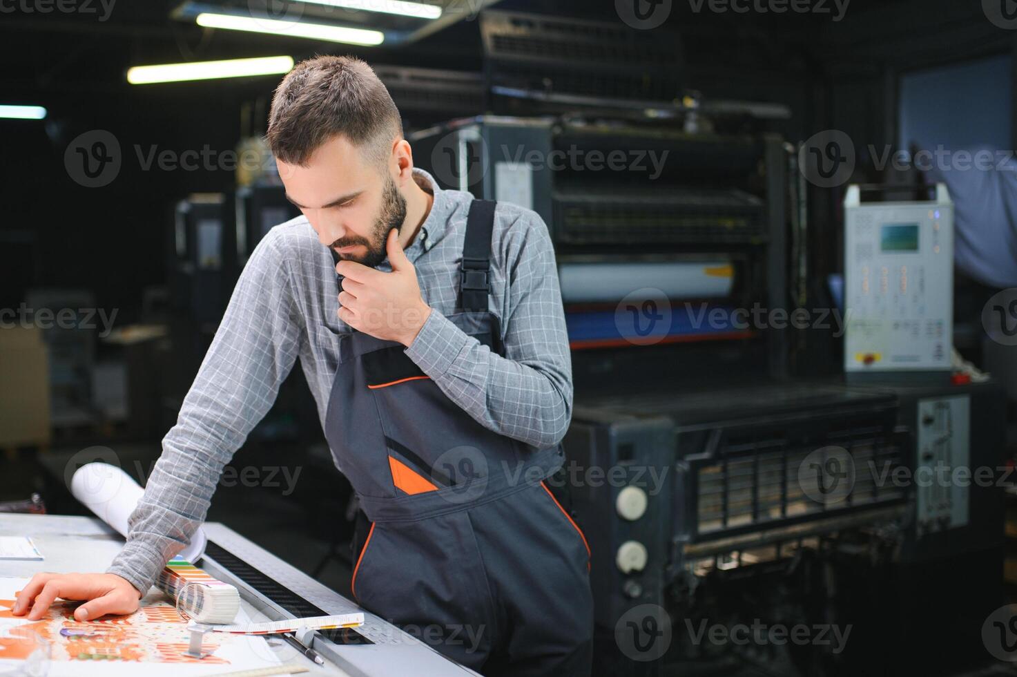 Print house worker controlling printing process quality and checking colors with magnifying glass photo