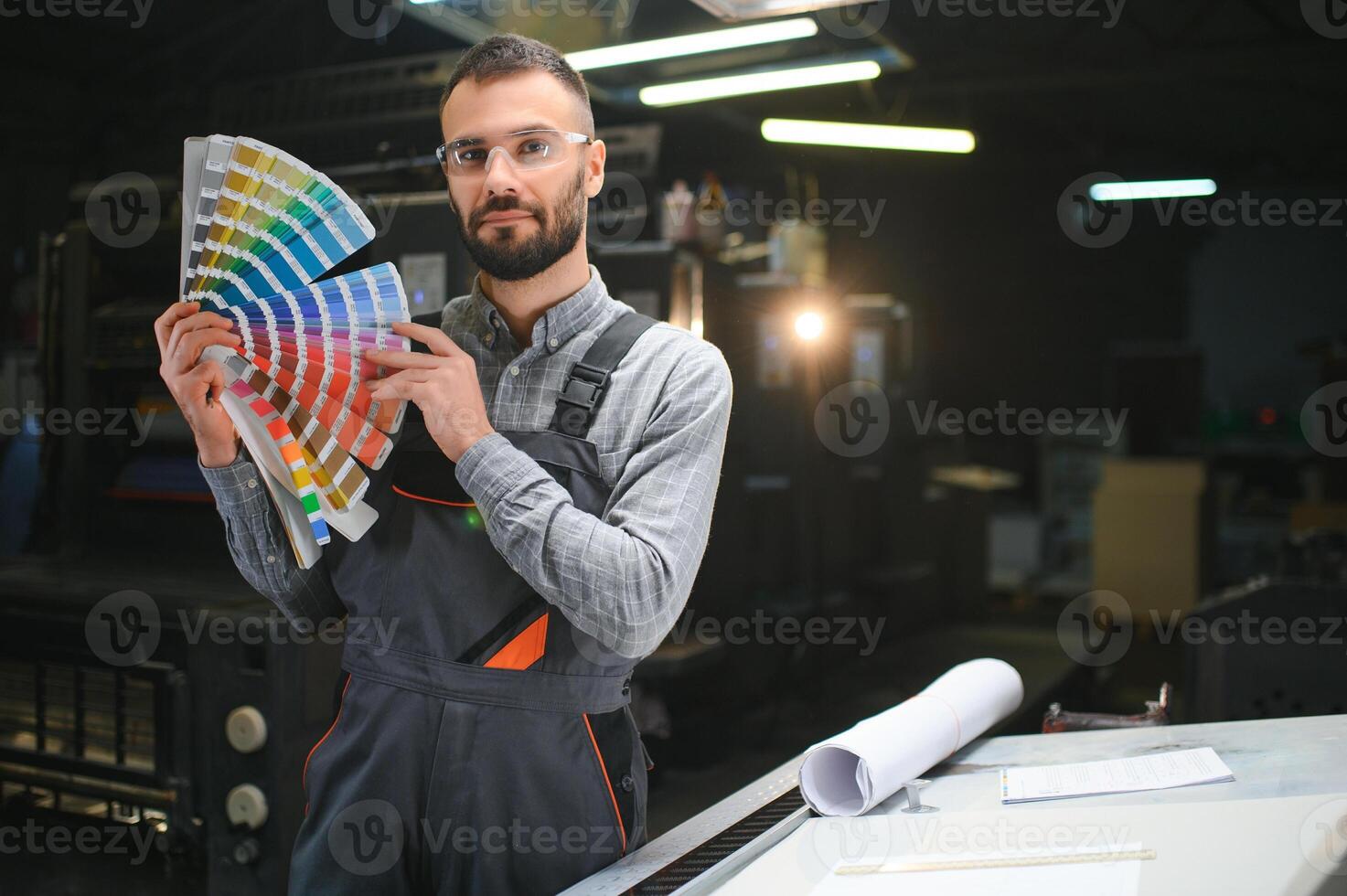 Man working in printing house with paper and paints photo