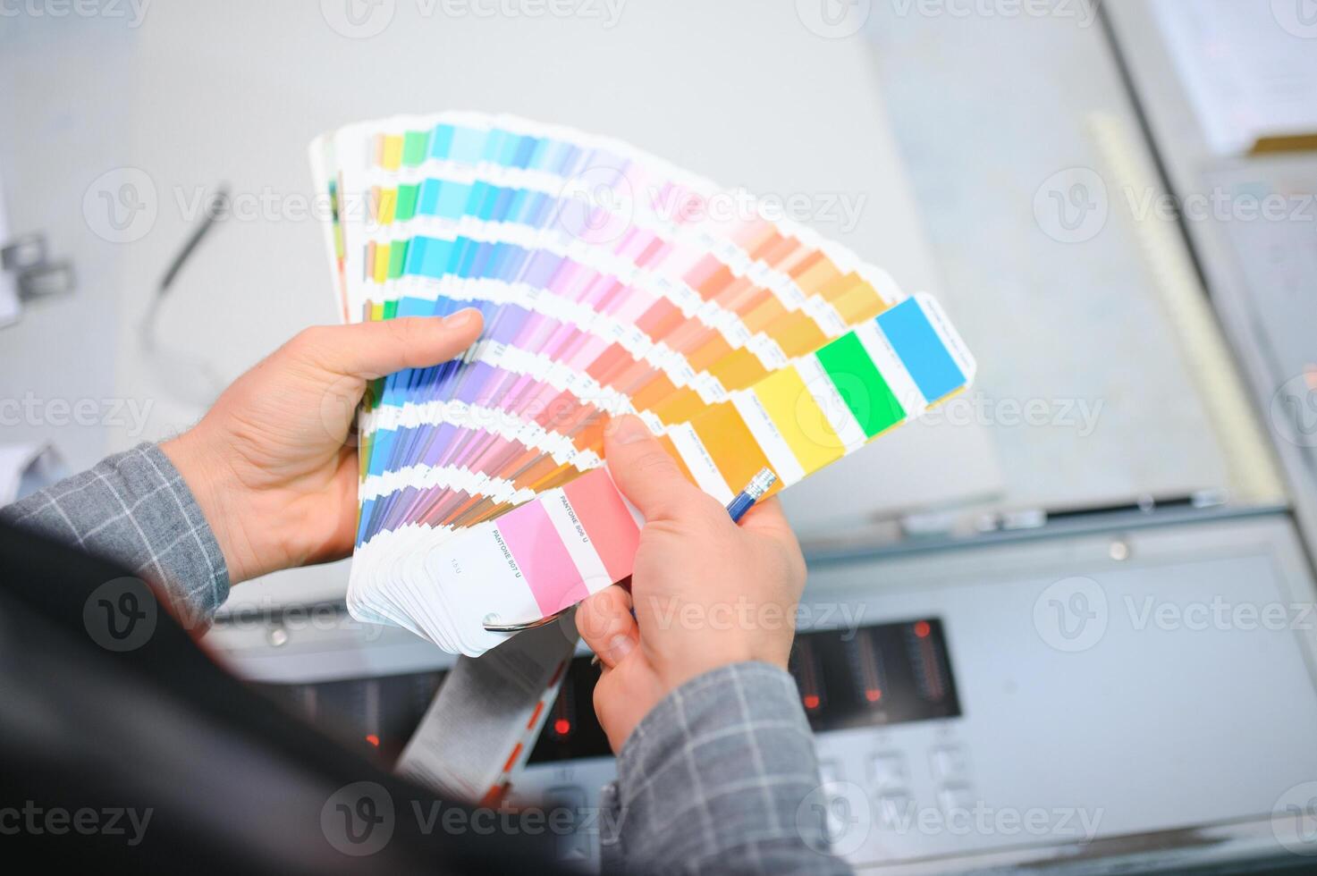 Print house worker controlling printing process quality and checking colors with magnifying glass photo