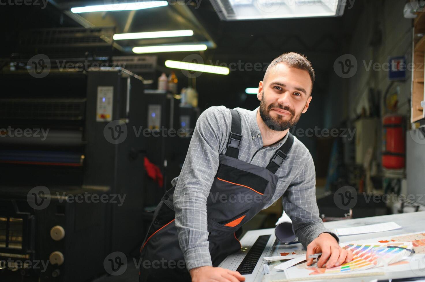 Print house worker controlling printing process quality and checking colors with magnifying glass photo