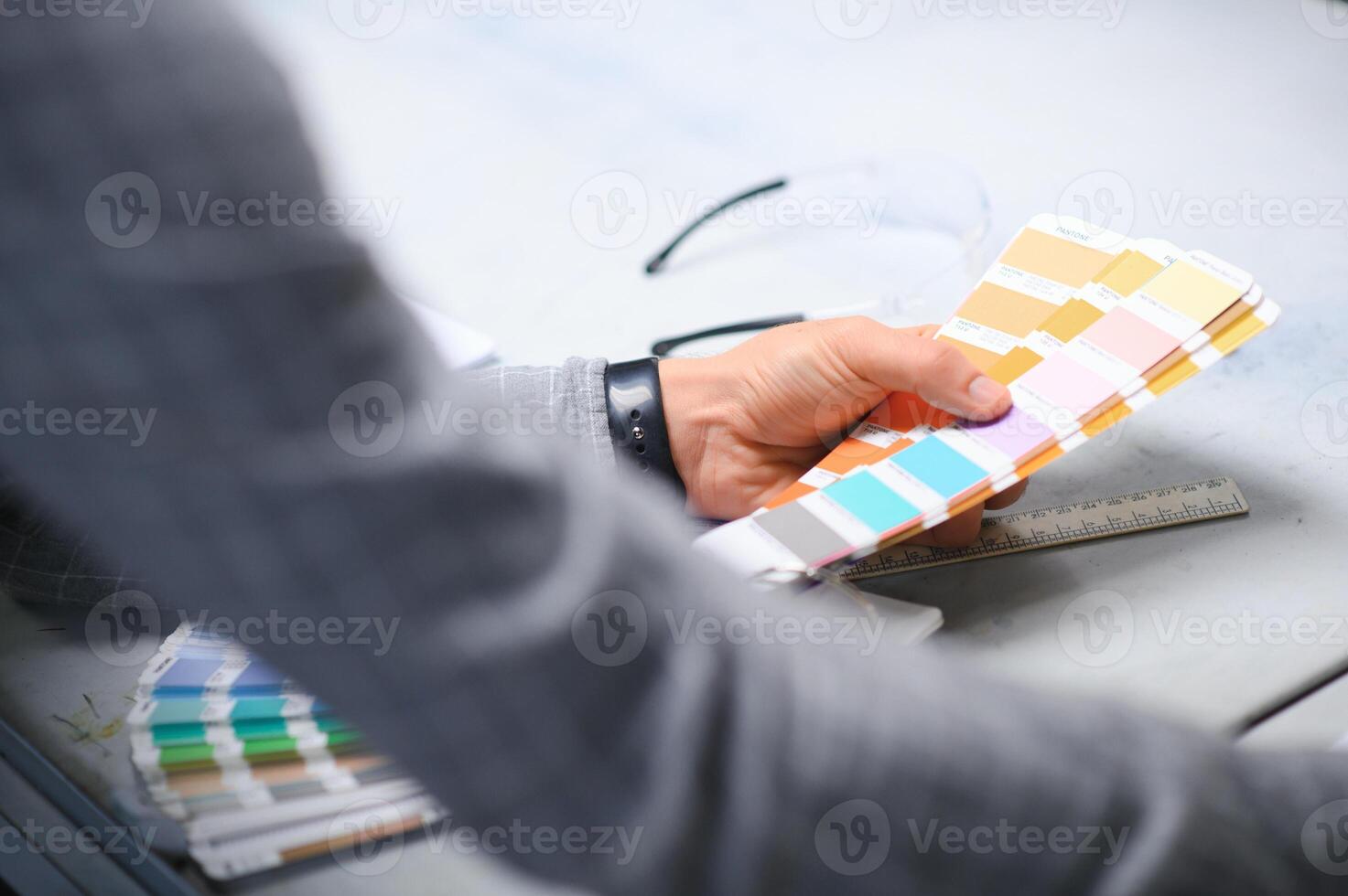 Print house worker controlling printing process quality and checking colors with magnifying glass photo