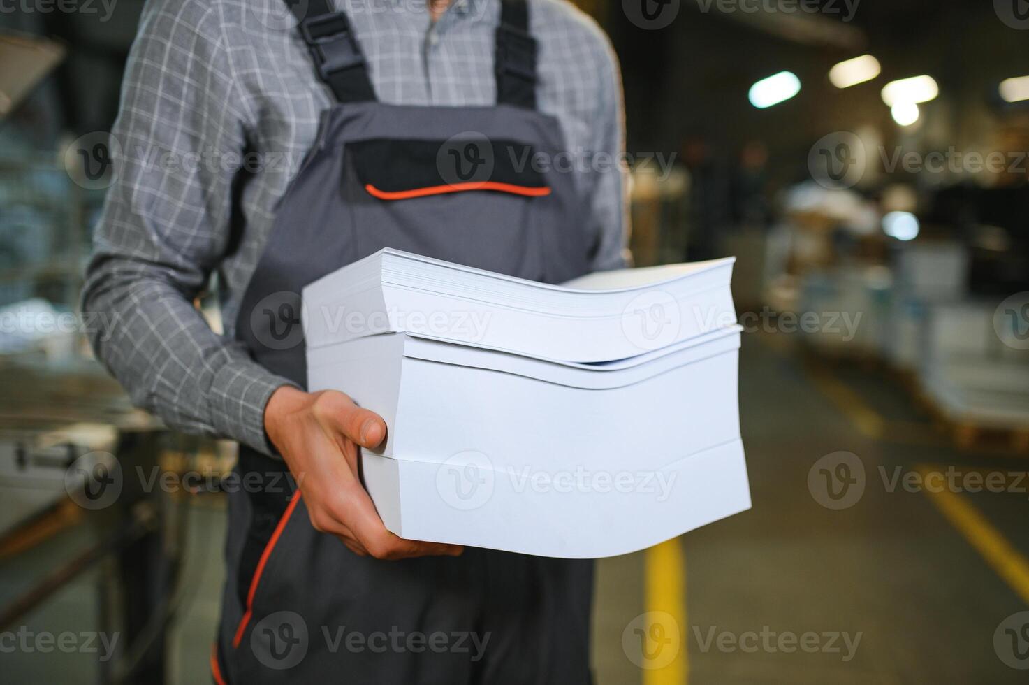 Close up of man putting stack of paper in printing machine at publishing shop, copy space photo