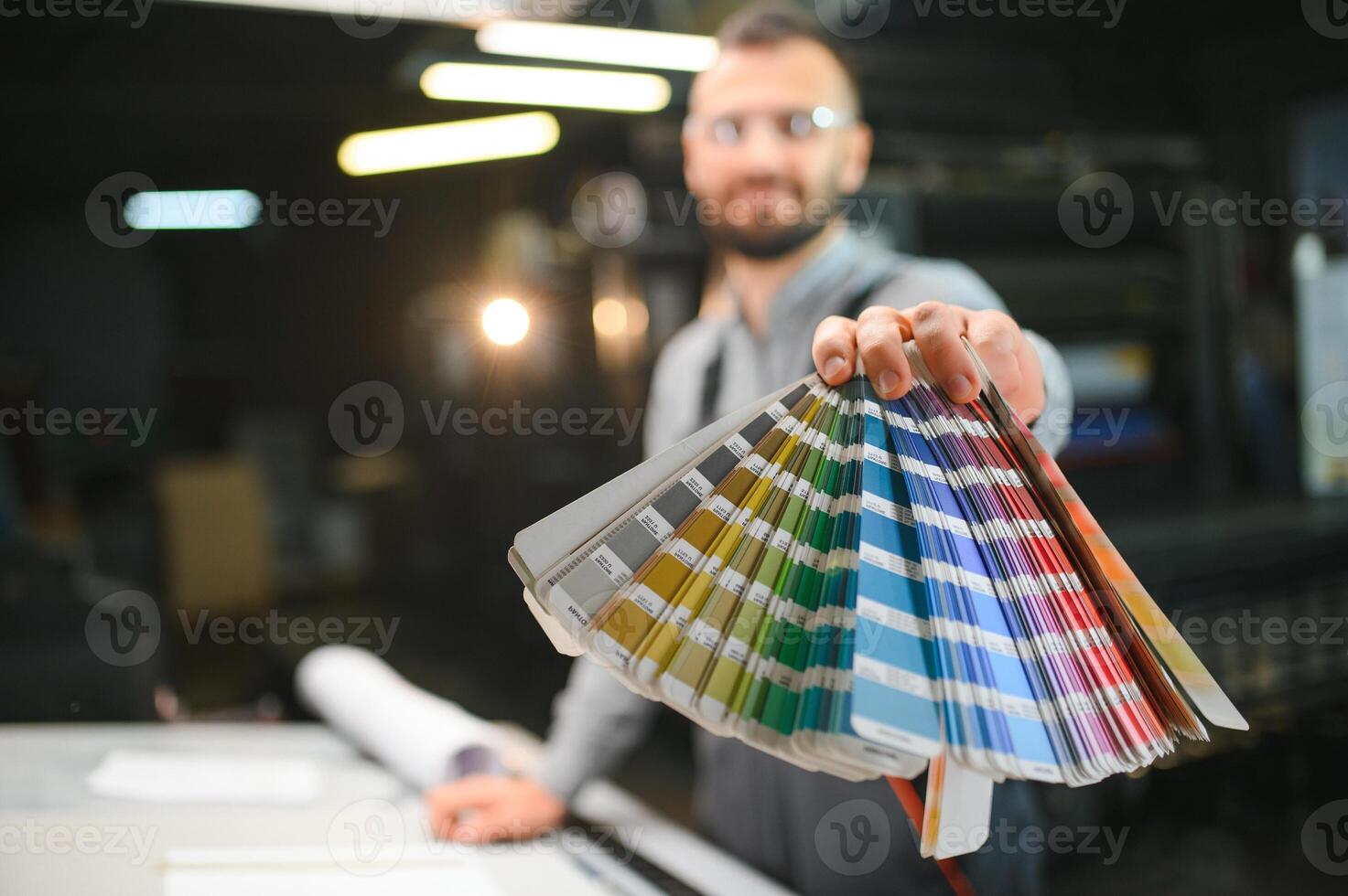 Man working in printing house with paper and paints photo