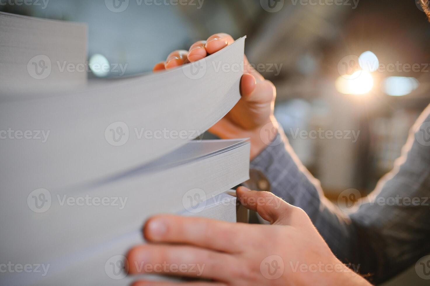 Close up of man putting stack of paper in printing machine at publishing shop, copy space photo