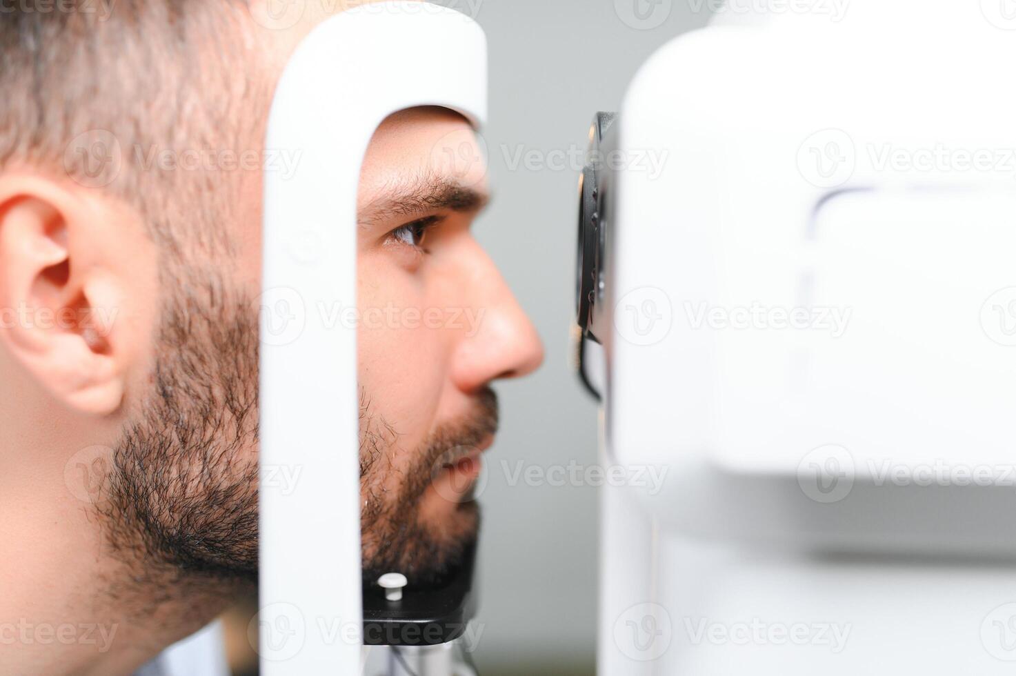 hermoso hombre consiguiendo un ojo examen a oftalmología clínica. comprobación retina de un masculino ojo foto