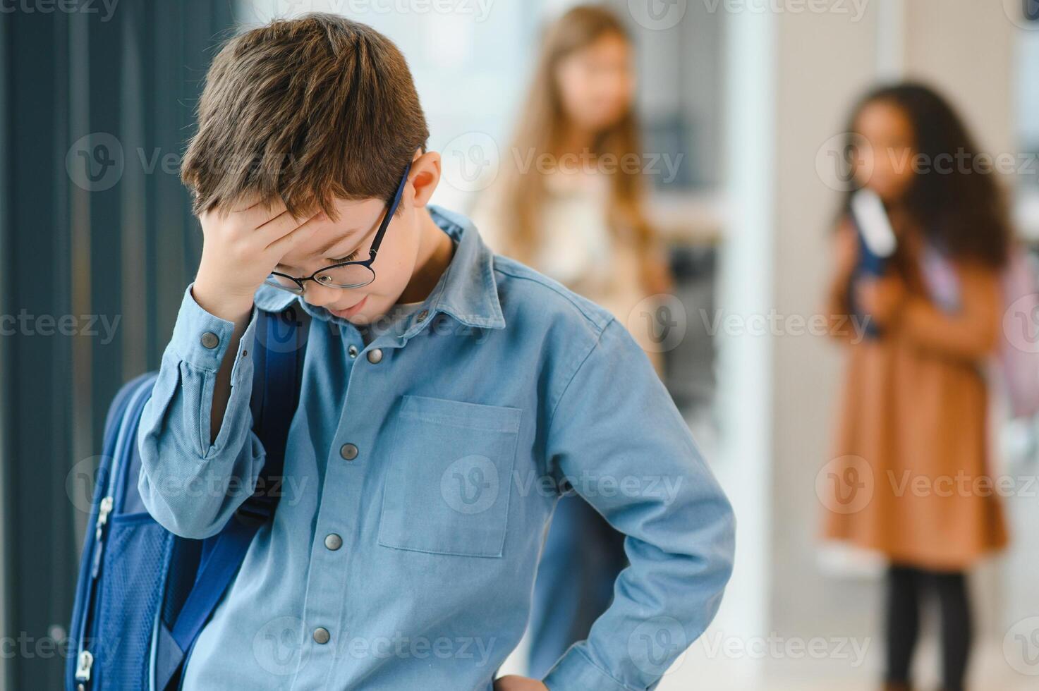 School friends bullying a sad boy in corridor at school photo