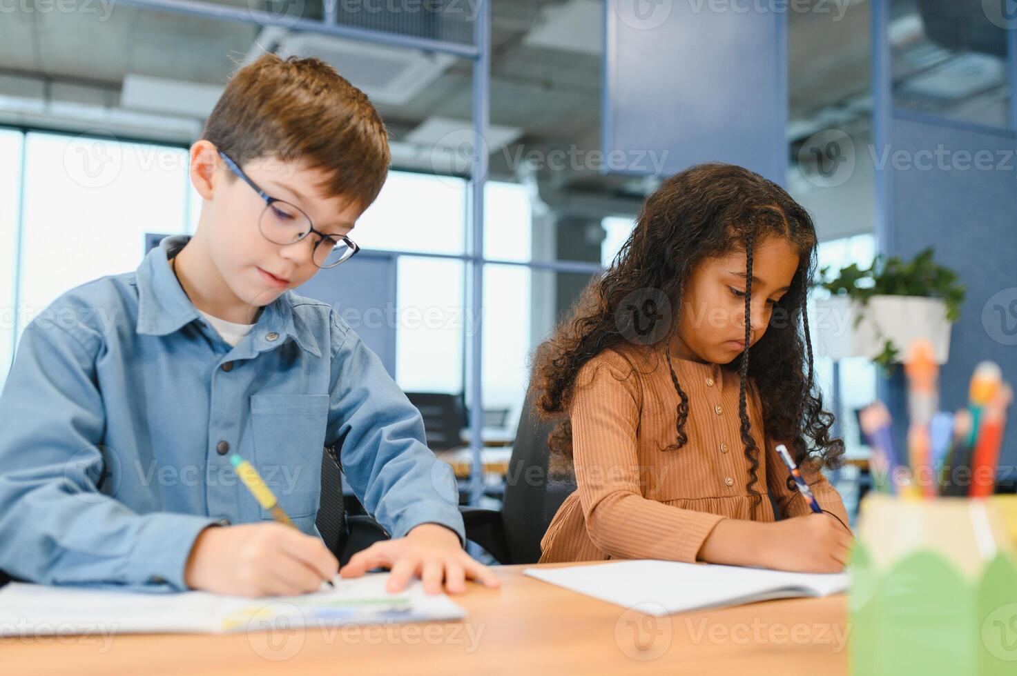 enfocado multirracial estudiantes niños escritura abajo datos dentro cuaderno mientras sentado a mesa foto