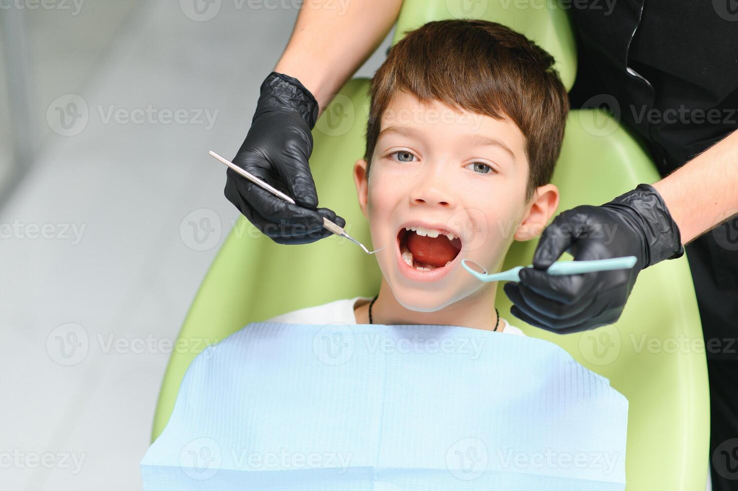 Dentist examining little boy's teeth in clinic photo